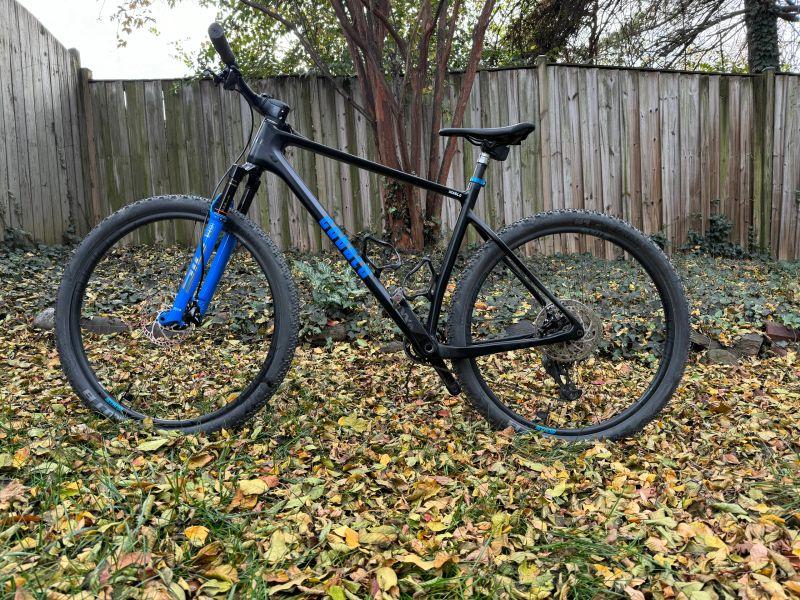 Black and blue Cobalt hardtail mountain bike beside a wooden fence